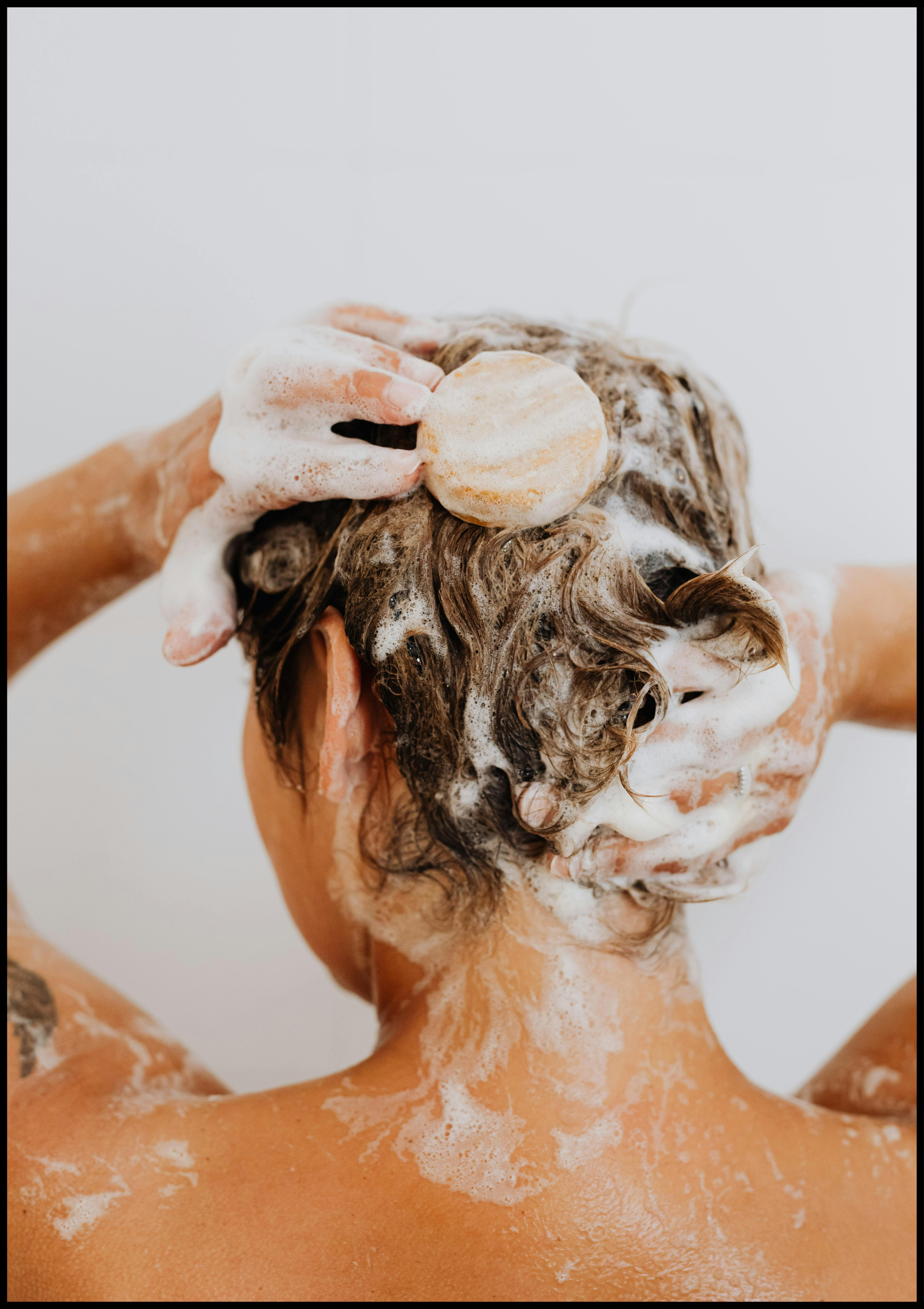 Eine Person wäscht sich die Haare mit einem Shampoo.