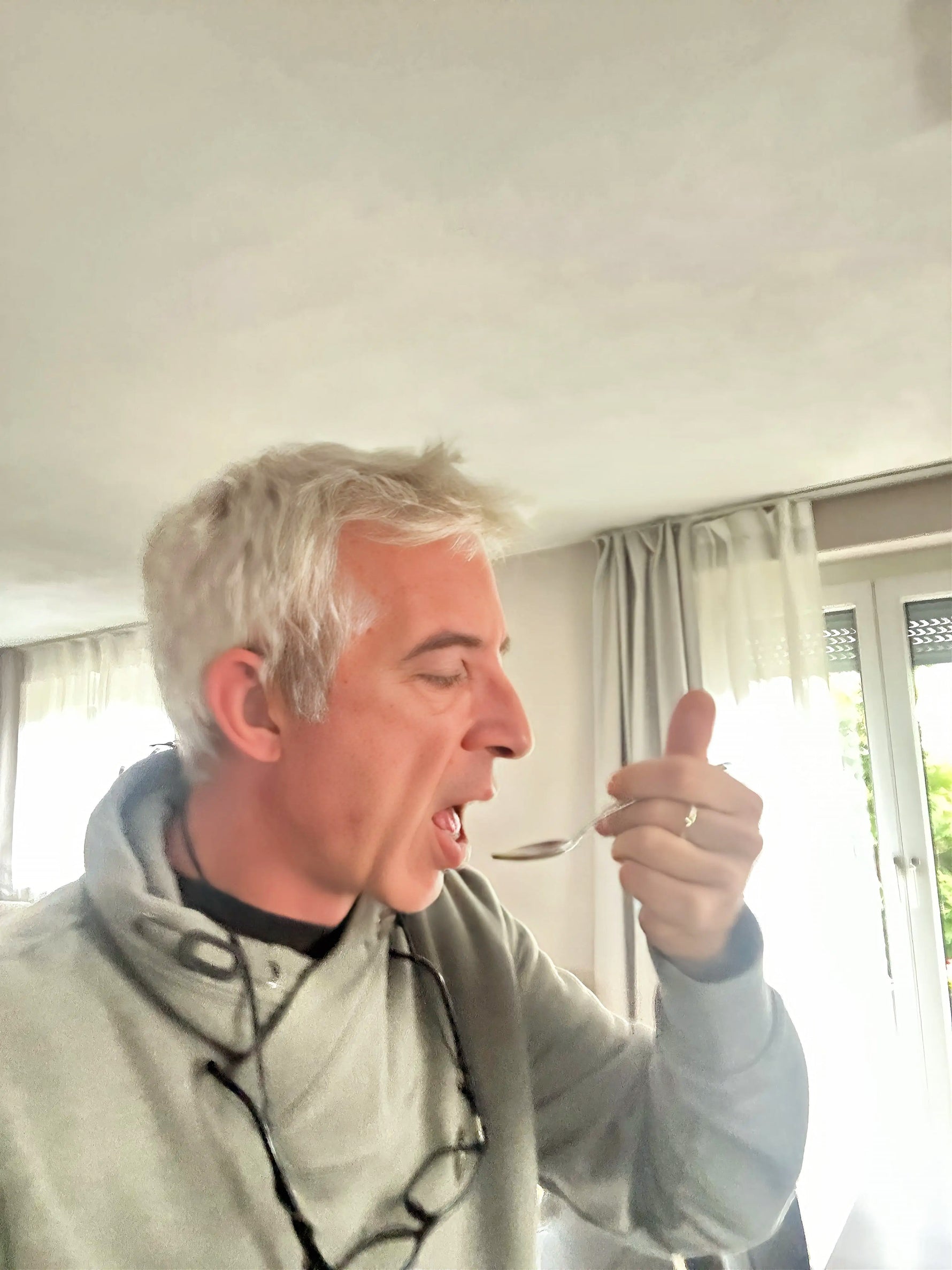 Eine männliche Person nimmt einen Teelöffel mit Oliven- und Oreganoöl ein.