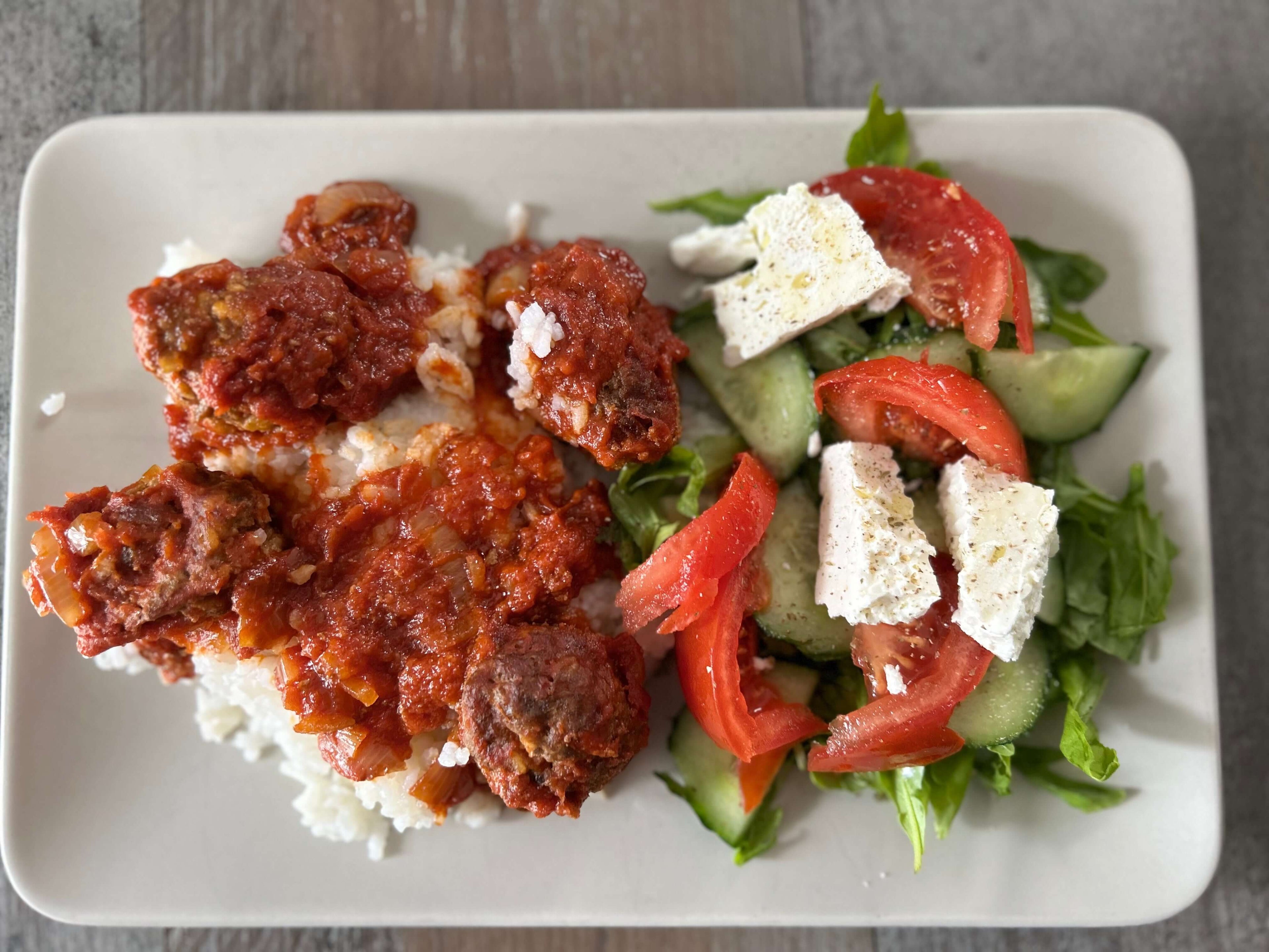 Ein Teller mit Pfefferminzöl-Soutsoukakia, Reis und einem griechischen Salat.