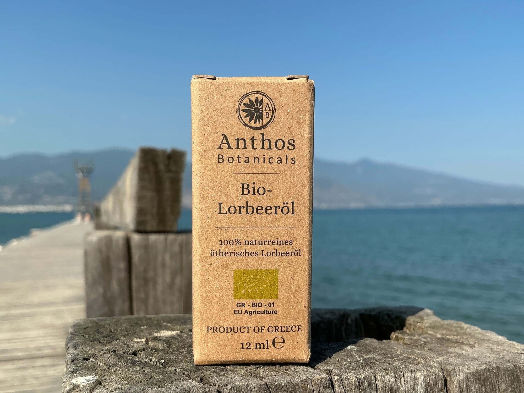 Eine Kraftverpackung mit ätherischem Lorbeeröl auf einem Holzsteg am Meer.