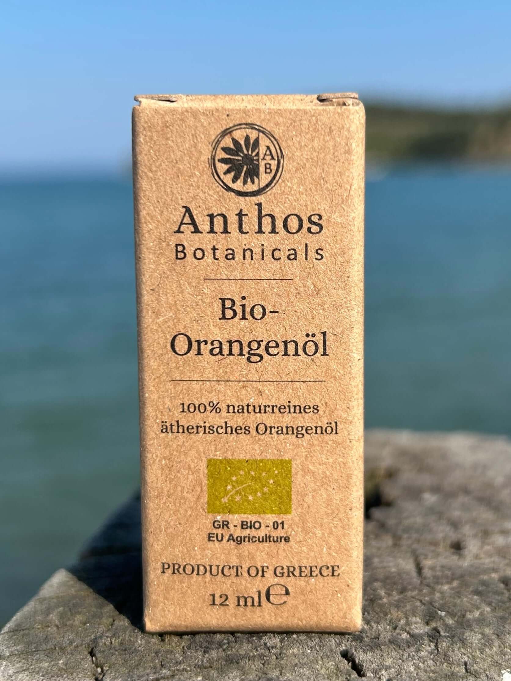 Eine braune Kraftverpackung mit ätherischem Orangenöl Bio auf einem Holzsteg am Meer. 