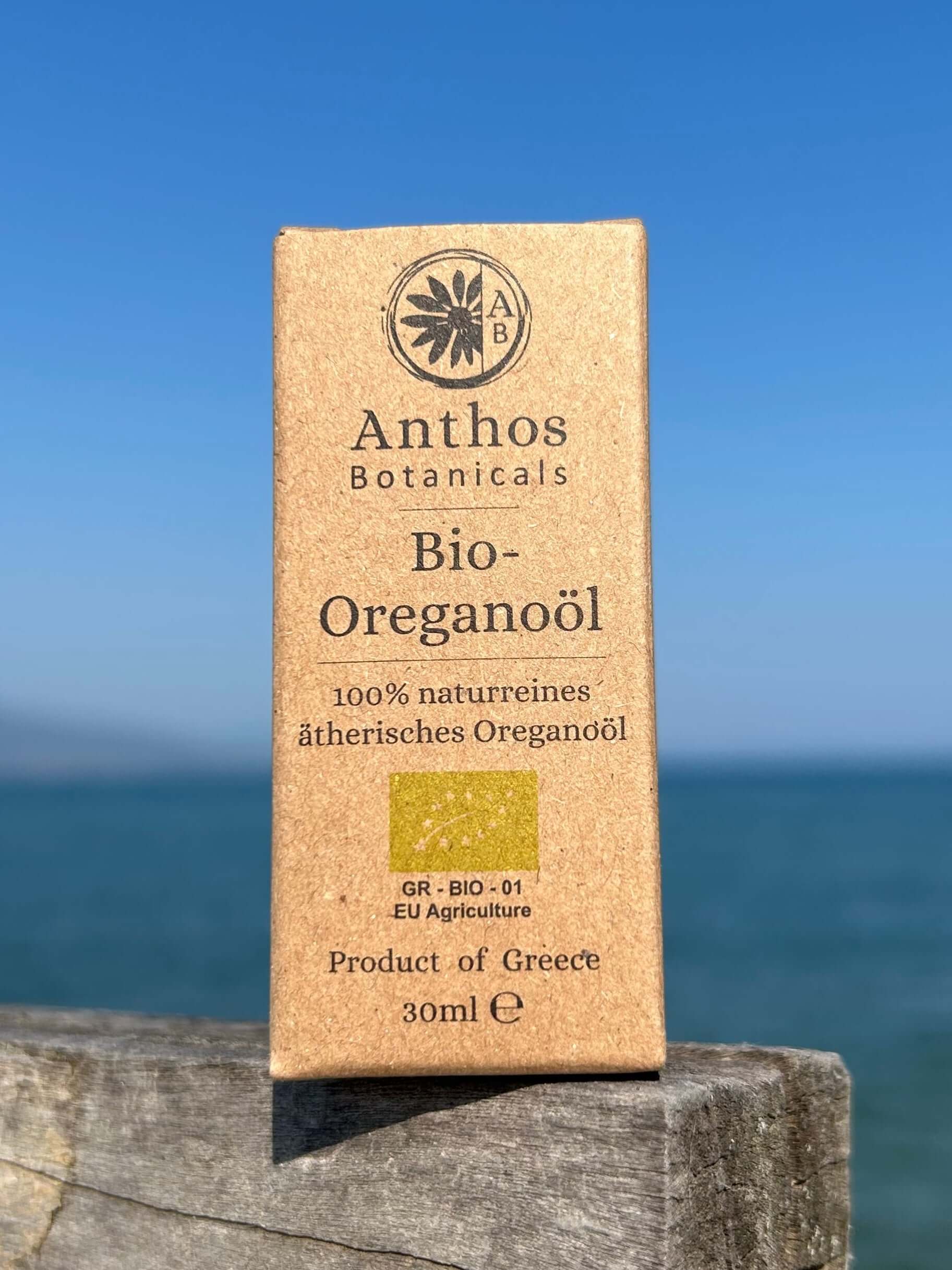 Braunglasflasche mit biologischem Oreganoöl auf einem Holzsteg am Meer.