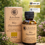 Kraftverpackung und Braunglasflasche mit Thymianöl bio 30 ml von Anthos Botanicals auf einem Felsen in der Natur.