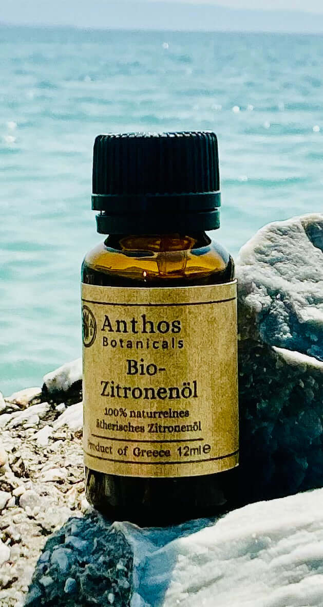 Eine Braunglasflasche mit ätherischem Bio-Zitronenöl auf einem Felsen am Meer.