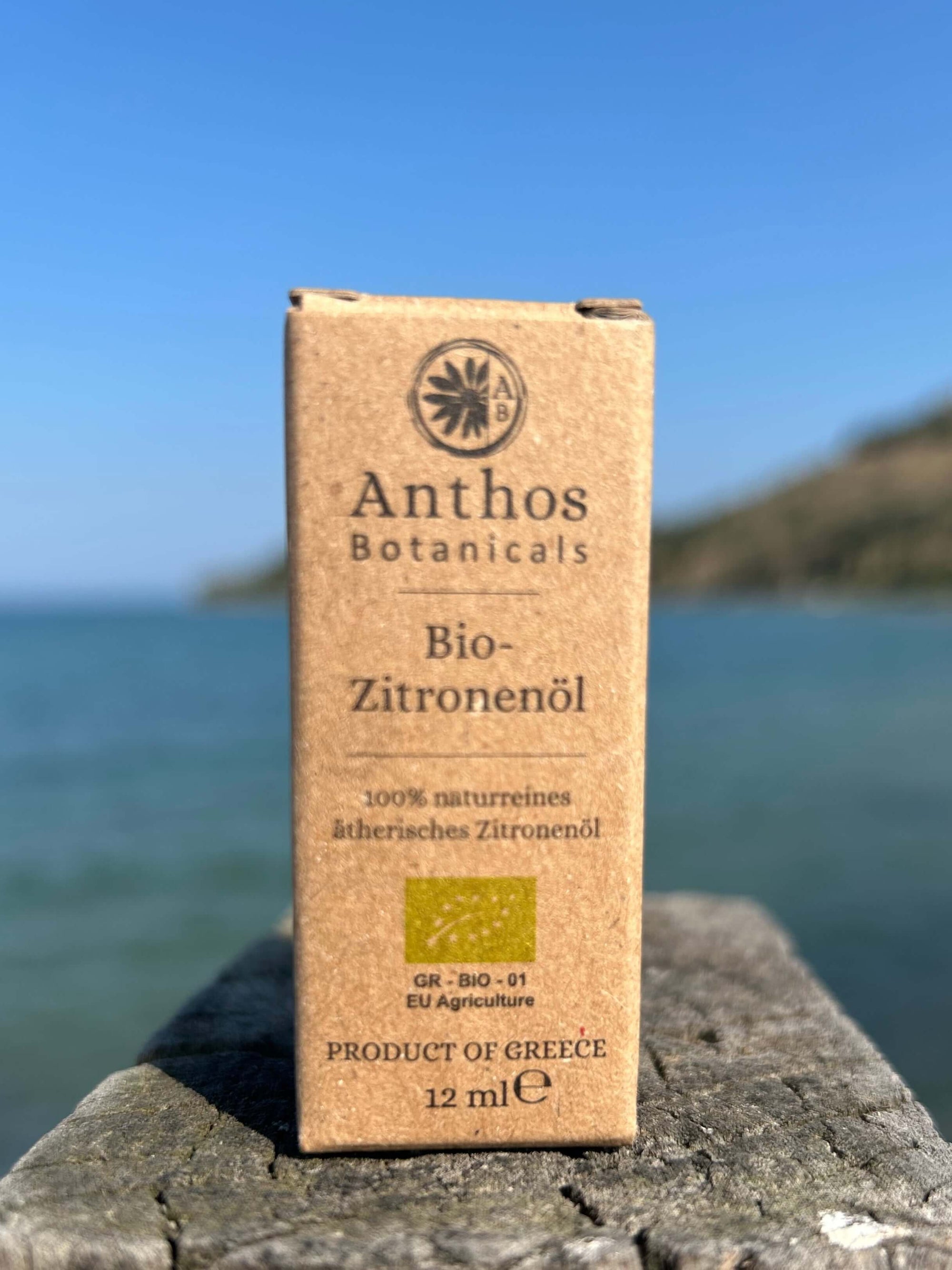Eine Kraftverpackung mit ätherischem Zitronenöl aus biologischem Anbau auf einem Holzpfahl am Meer.