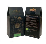 Zwei schwarze Verpackungen mit goldener  Schrift sowie aufgedruckten Pflanzen. Ein Sichtfenster ist vorhanden und man erkennt Zitronenmelisse-Kräuter. 