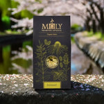 Eine schwarze Verpackung mit Griechischer Bergtee Bio sowie aufgedruckten Pflanzen. Ein Sichtfenster ist vorhanden und man erkennt Blüten des griechischen Bergtees. 