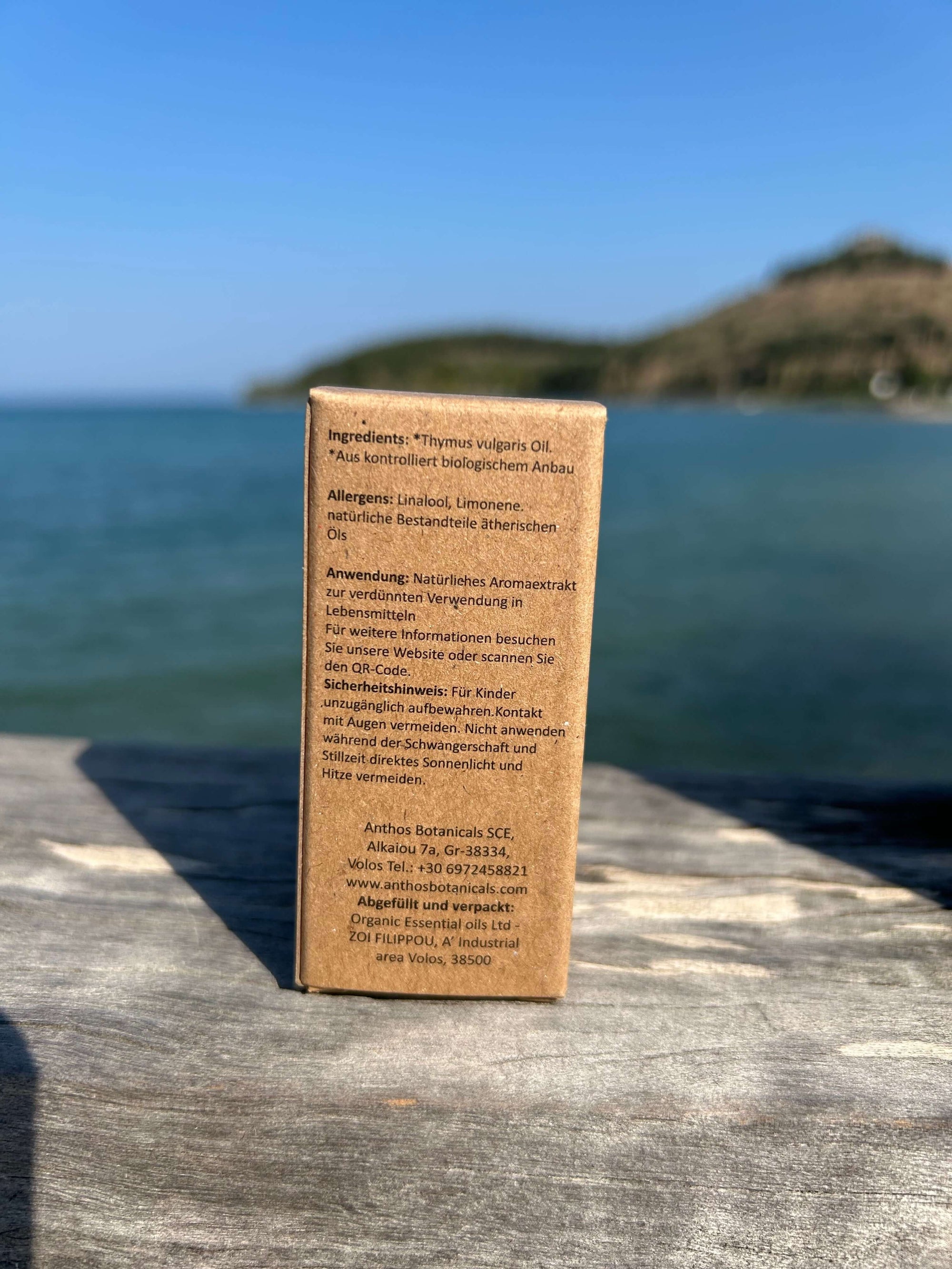 Rückseite einer Kraftverpackung mit Bio-Thymianöl auf einem Holzsteg.