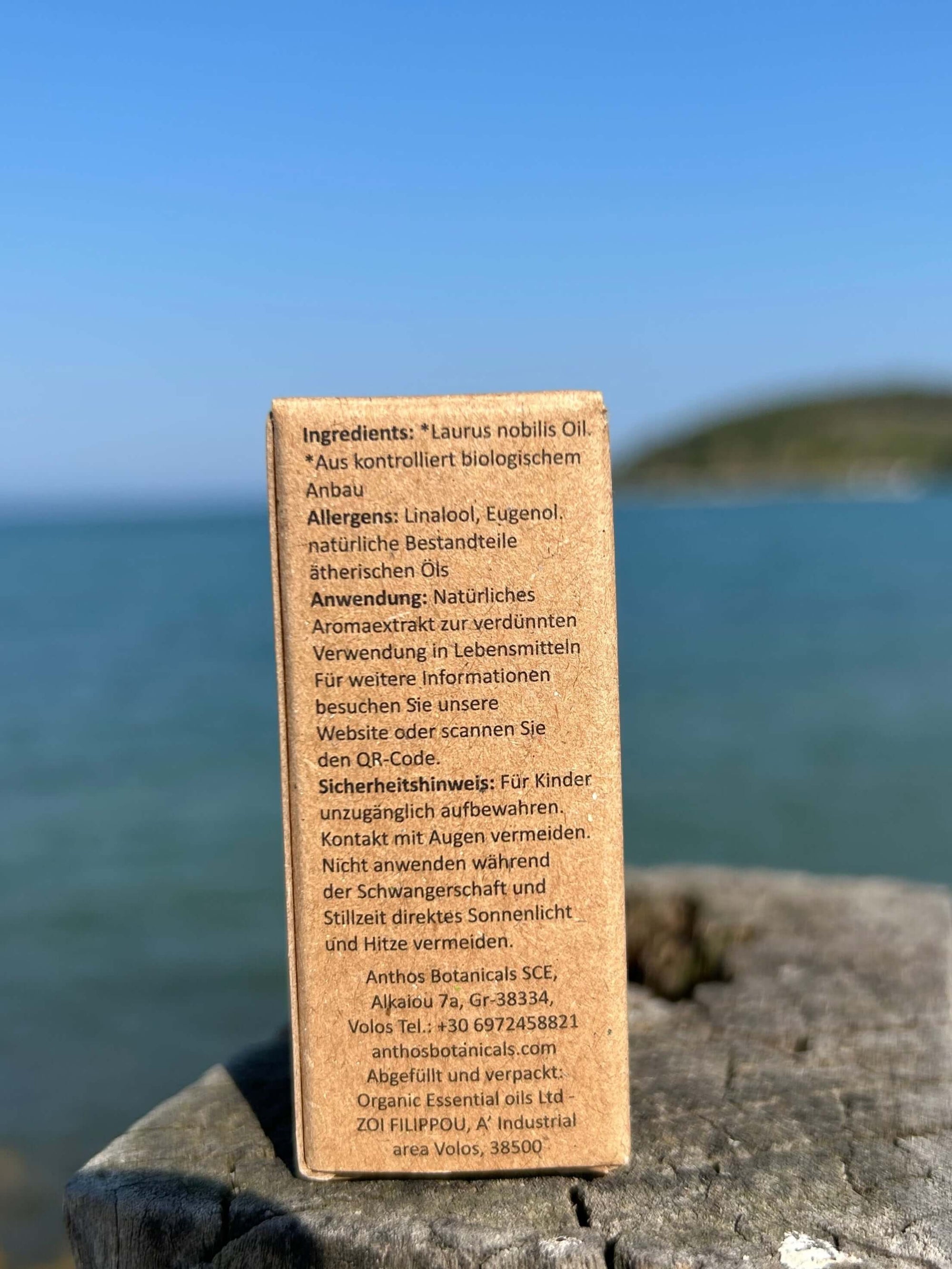Rückseite einer Kraftverpackung mit ätherischem Lorbeeröl auf einem Holzsteg am Meer.