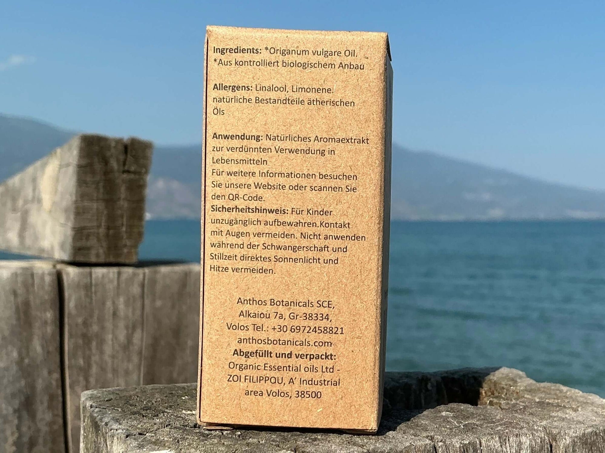 Die Rückseite einer Kraftverpackung von biologischem Oreganoöl mit Hinweisen auf einem Holzbalken am Meer.