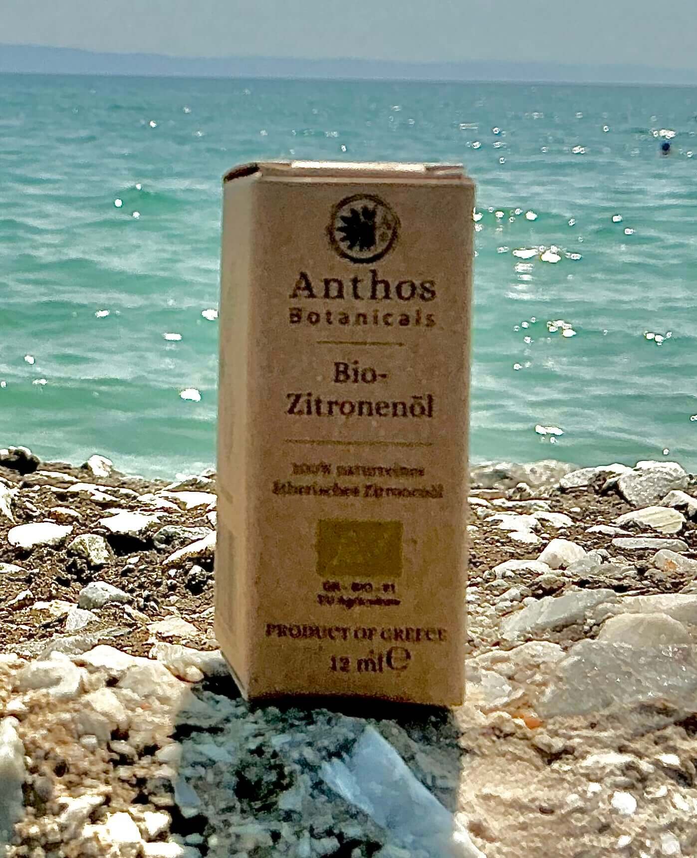 Eine braune Kraftverpackung  mit ätherischem Zitronenöl aus biologischem Anbau auf einem Felsen am Meer.