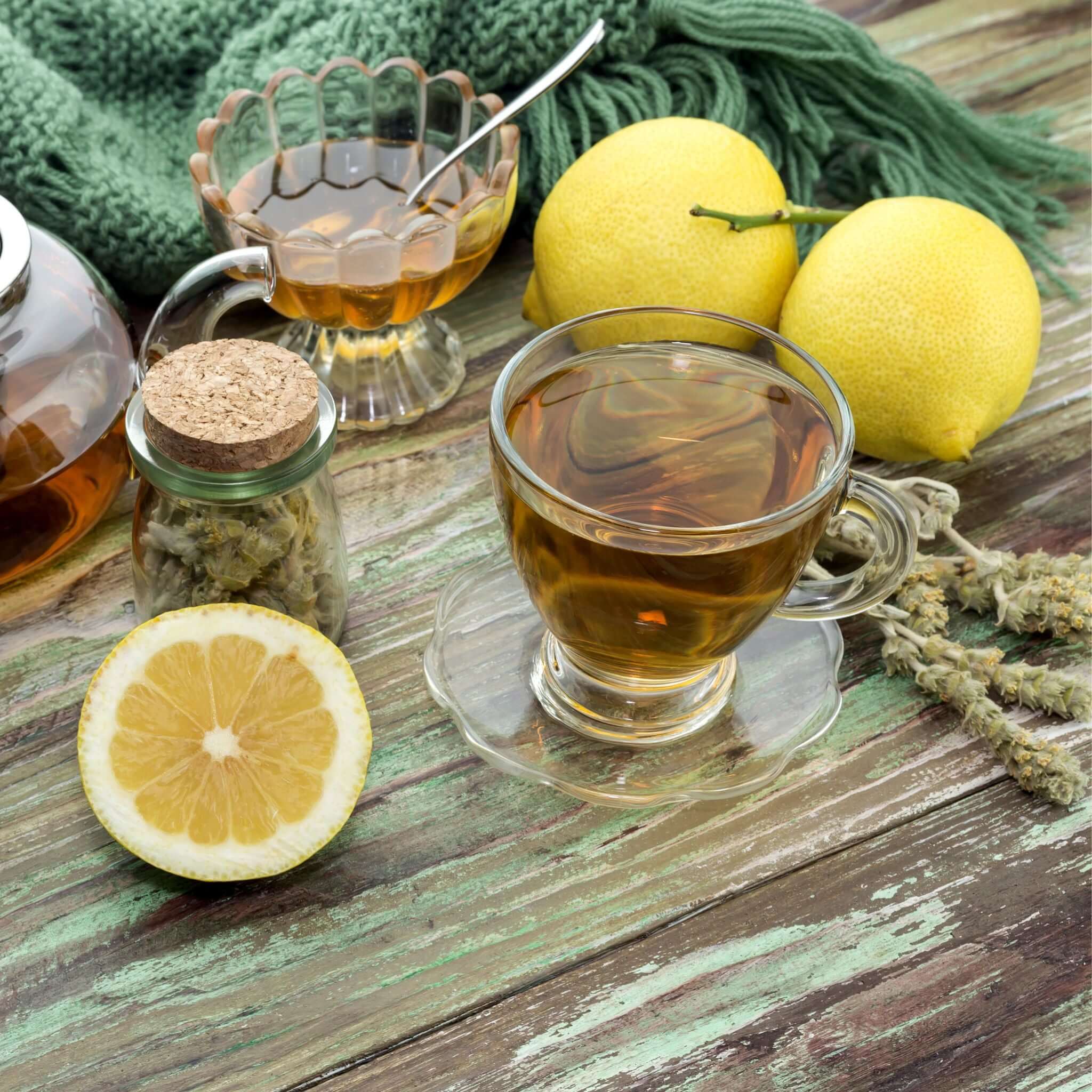 Griechischer Bergtee in Gläsern und einer Kanne mit Honig und Zitronen auf einem Tisch.