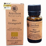 Eine Braunglasflasche mit ätherischem Orangenöl Bio von Anthos Botanicals neben seiner braunen Verpackung aus Kraftpapier.