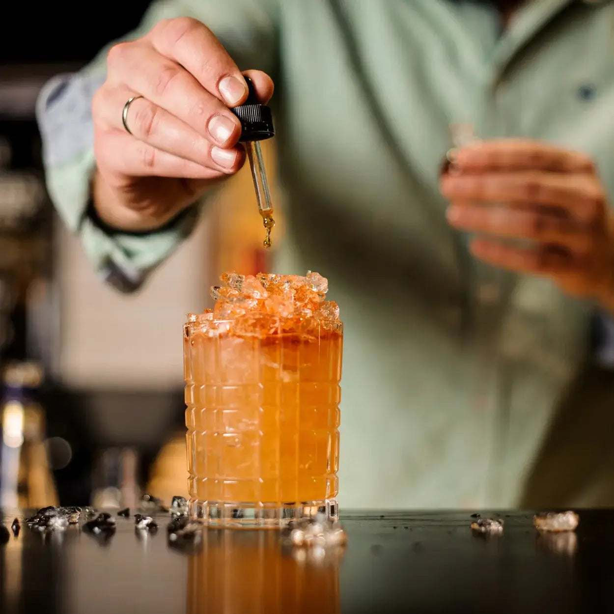 Ein Barkeeper mischt ätherisches Öl in einen Cocktail.