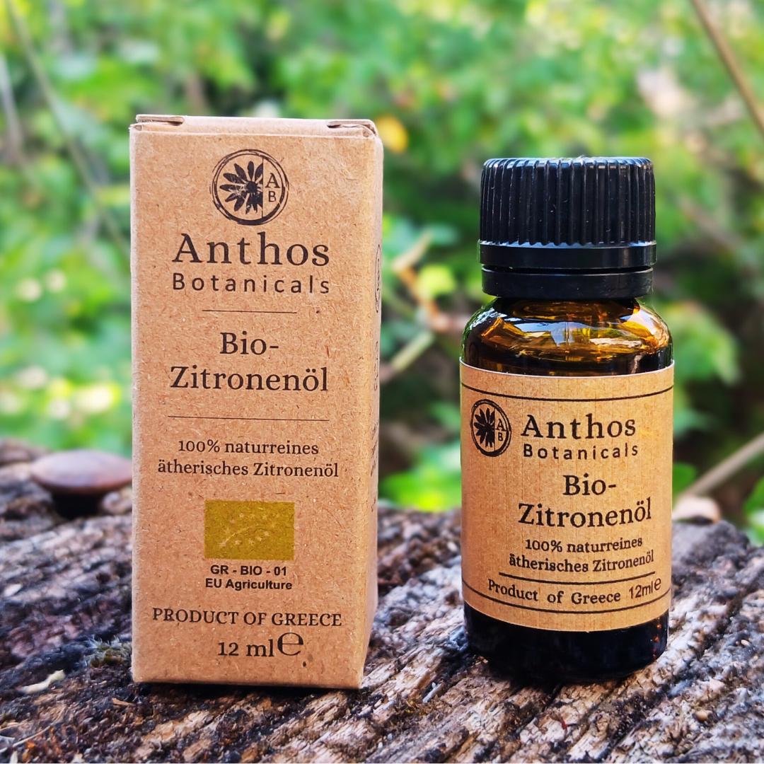Eine Kraftverpackung und eine Braunglasflasche mit ätherischem Bio-Zitronenöl auf einem Felsen in der Natur.